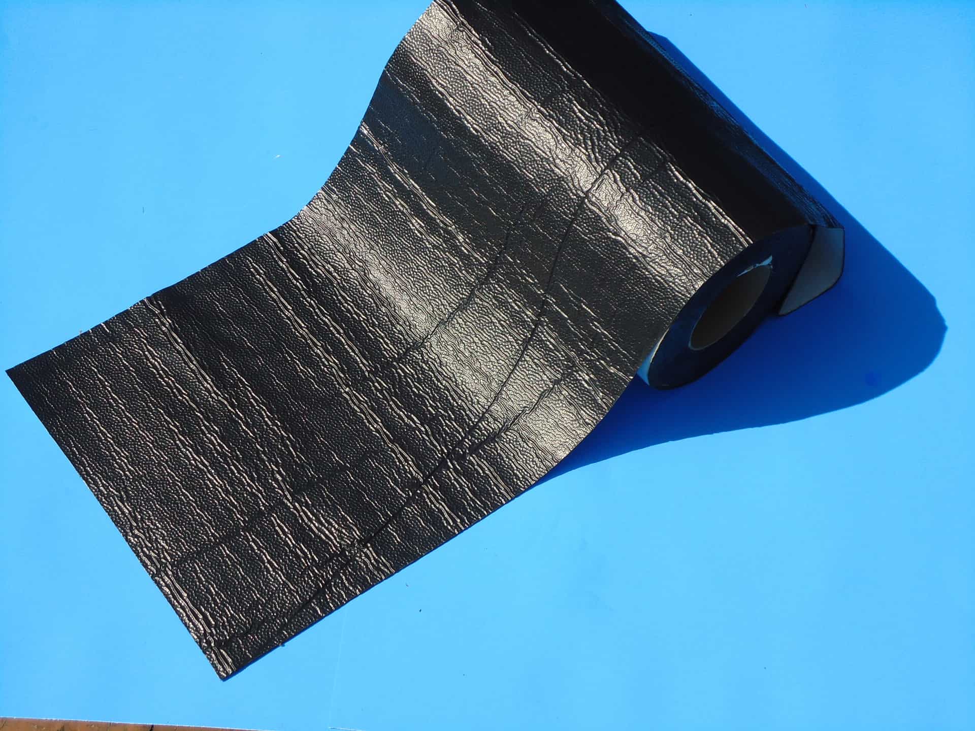 A roll of black duct tape on top of a blue surface.