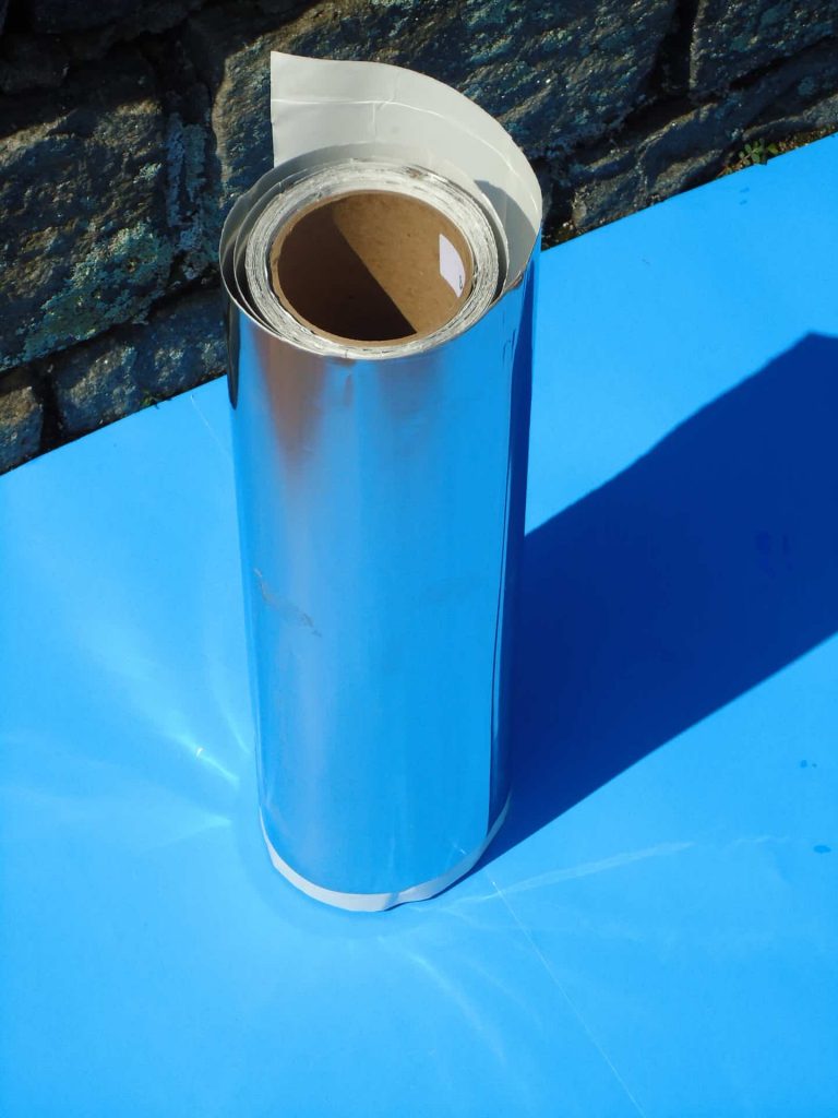 A roll of aluminum foil on top of a blue surface.