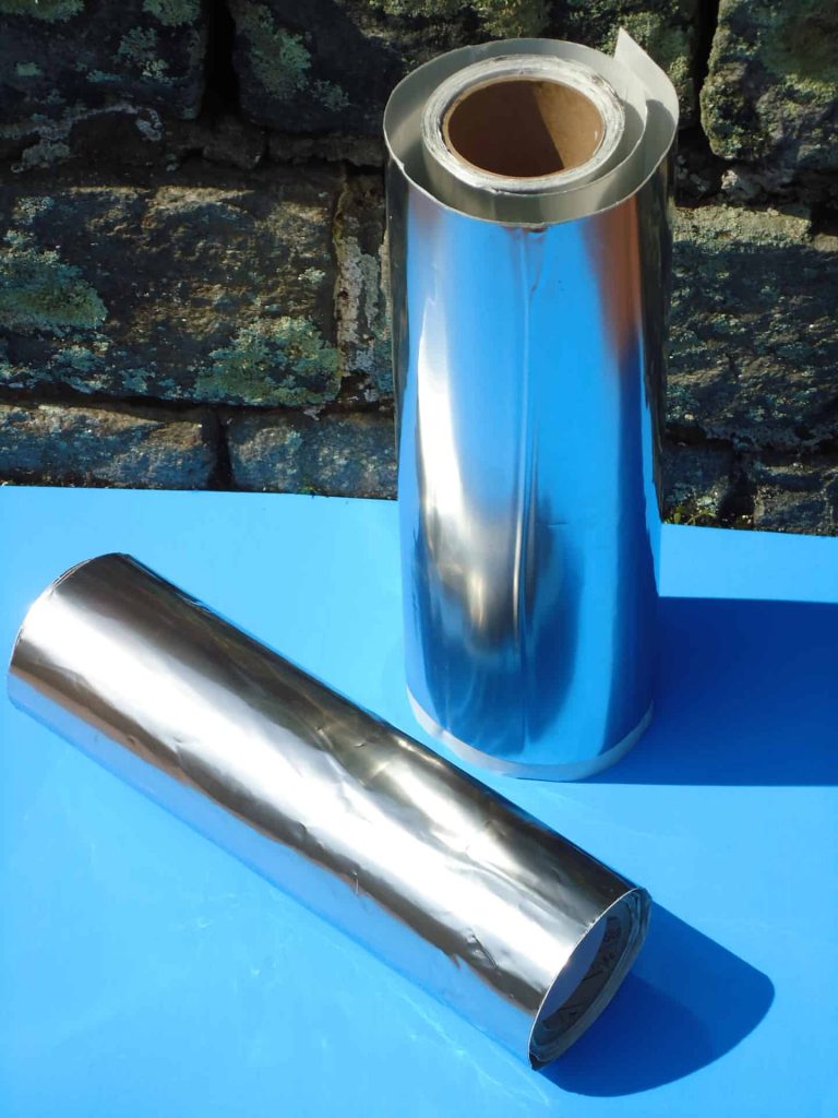 A silver vase and a metal cylinder on a blue table.