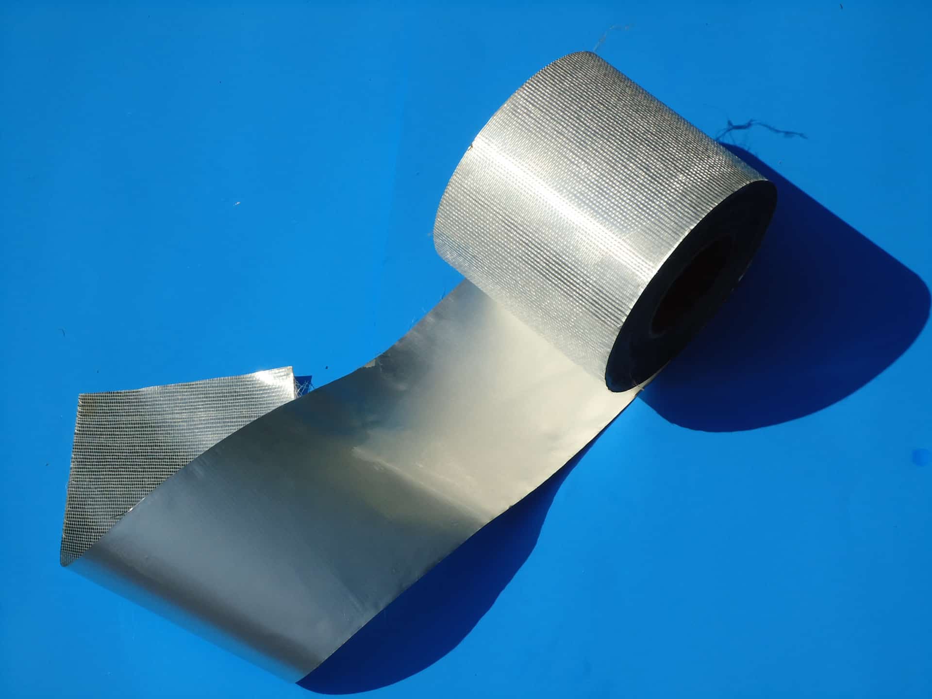 A roll of silver ribbon on top of blue background.